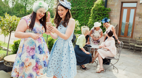 Women dressed up in dresses and hats to fit a festive wedding dress code